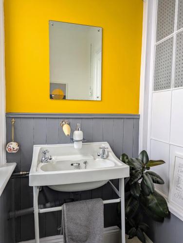 a bathroom with a white sink and a yellow wall at Family Home in Tywyn - Game and Cinema Rooms in Tywyn