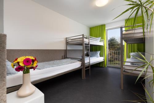 a room with two bunk beds and a vase with flowers at Jugendhaus Klipper Norderney in Norderney