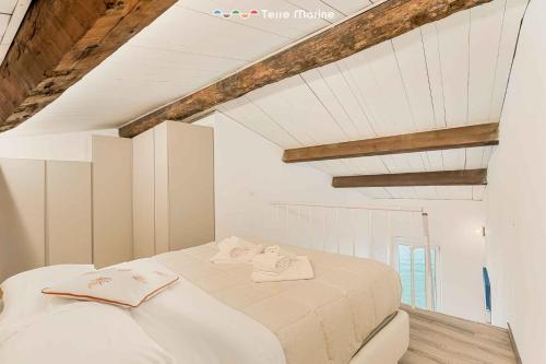 een wit bed in een kamer met houten plafonds bij Casa al Quarto, Terre Marine in Fezzano