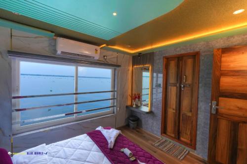een slaapkamer met een bed en een raam met uitzicht op de oceaan bij Karimeen Boathouse in Alleppey