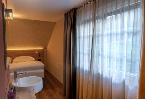 a bathroom with a sink and a bed and a window at Gasthof zum Reh - Self Check-in 