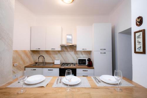 a kitchen with white cabinets and a table with wine glasses at Marcos Apartments I Bathtub in Bedroom experience in Făgăraş