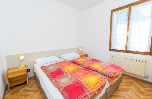 1 dormitorio con 1 cama con un edredón colorido en Casa Luisella, en Pieve di Ledro