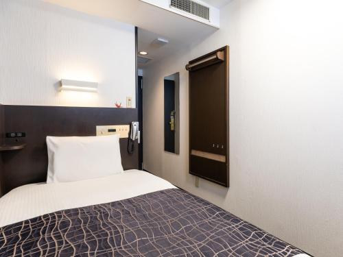 a small bedroom with a bed and a window at APA Hotel Osaka Kadomashi Ekimae in Kadoma