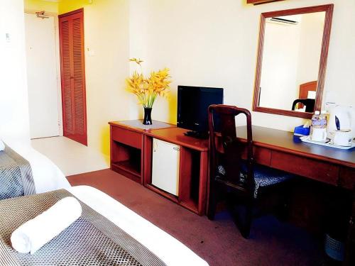 a bedroom with a desk with a computer and a mirror at Global Hotel Labuan in Victoria Town