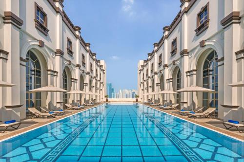 a swimming pool in the middle of a building with chairs at Oaks Ibn Battuta Gate Dubai in Dubai