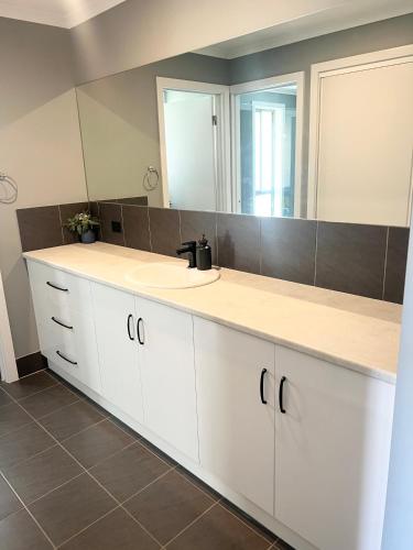 a bathroom with two sinks and a large mirror at Telopea House Mount Gambier in Worrolong