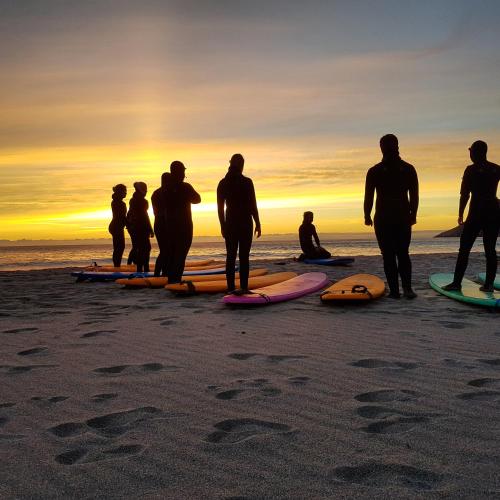a group of people standing on a beach with surfboards at Unstad Arctic Resort in Unstad