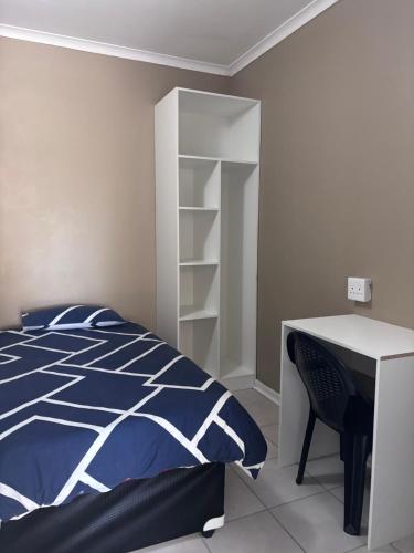 a bedroom with a bed and a desk and shelves at The Easy Stay in Durban