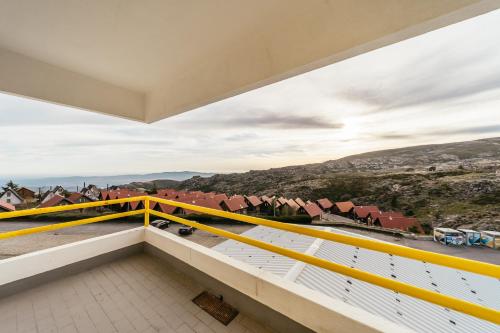 a balcony with yellow railing and a view of houses at EntreVales Serra da Estrela in Penhas da Saúde