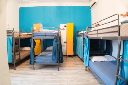 Habitación con 3 literas y pared azul. en Victoria House Hostel, en Génova