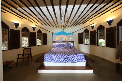 a bedroom with a bed in a room with windows at Unguja Lodge in Kizimkazi