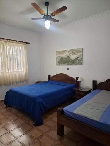 a bedroom with two beds and a ceiling fan at Casa Térrea Espaçosa Centro , Bertioga-Pertinho da Praia in Bertioga