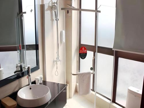 a bathroom with a sink and a glass shower at GreenTree Inn Linyi Bus Station in Linyi