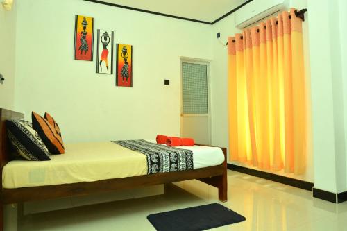 a bedroom with a bed with orange curtains at Royal Residence Negombo in Negombo