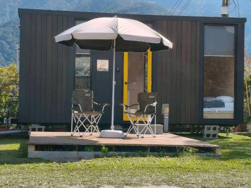 un paio di sedie e un ombrellone di fronte a un edificio di Cloudview Cottages by Tiny Away a Huan-shan