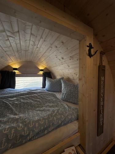 un letto in una casetta con soffitto in legno di Schlaffass am Sund ad Altefähr