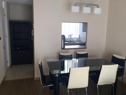 ein Esszimmer mit einem schwarzen Tisch und weißen Stühlen in der Unterkunft Departamento Marina la Serena in La Serena