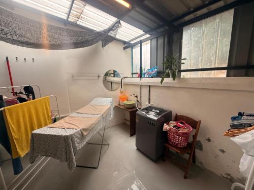 een ziekenhuiskamer met een tafel, een bed en een raam bij Just House - Rooms & Curios in George Town