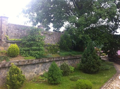 a garden with a stone wall and trees and bushes at Gnizdo Golubky in Shaian