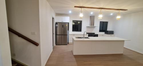 a white kitchen with a counter and a refrigerator at Redhill Batemans Bay in Batemans Bay