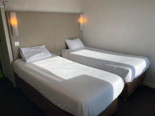 Dos camas en una habitación de hotel con sábanas blancas. en Campanile Valence Sud, en Valence