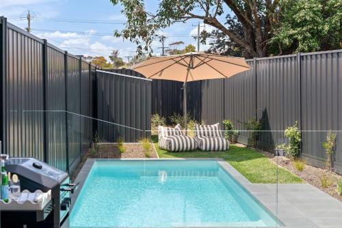 een zwembad met een parasol naast een hek bij Poolside Luxury Villa - Solar Pool Beach 3min in Mornington