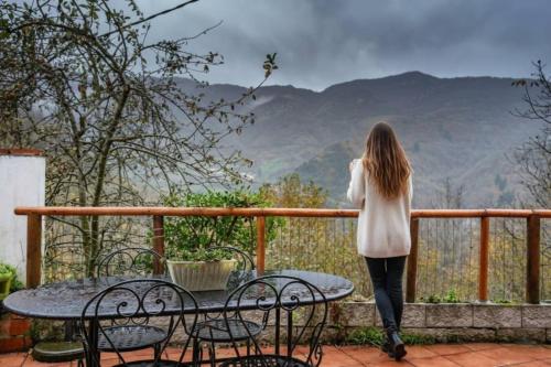 una donna in piedi su un balcone che guarda le montagne di El Ablanu Senda del Oso a Proaza