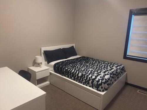 a bedroom with a black and white bed and a window at Panorama Haven in Calgary