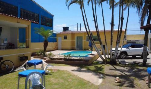 une cour avec une piscine et des palmiers dans l'établissement Pousada Perolas de Itanhaem, à Itanhaém