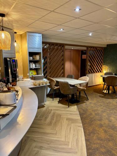 een keuken met een tafel en stoelen in een kamer bij Hôtel Le Pavillon de Saint-Lô - anciennement Lunotel in Saint Lo