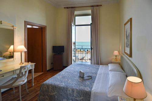 a bedroom with a desk and a bed with a view at Grand Hotel De Londres in Sanremo