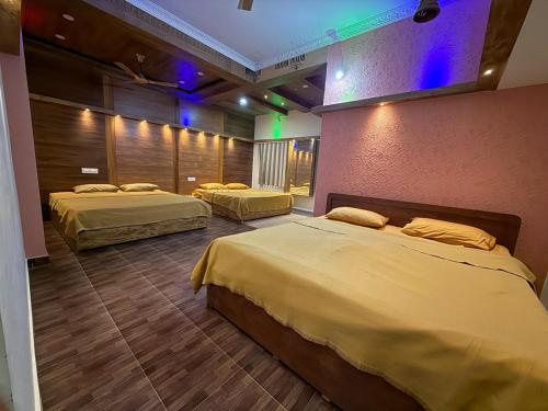 een slaapkamer met twee bedden en een muur met paarse lampen bij Palmstone Retreat in Gādigarpālya