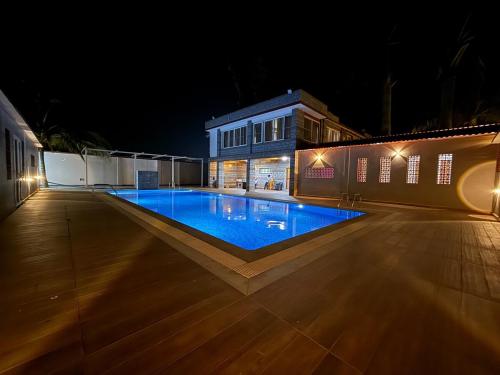 een zwembad 's nachts met een gebouw bij Palmstone Retreat in Gādigarpālya