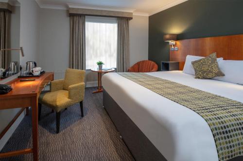 a hotel room with a large bed and a desk at Best Western Plus Angel Hotel in Chippenham
