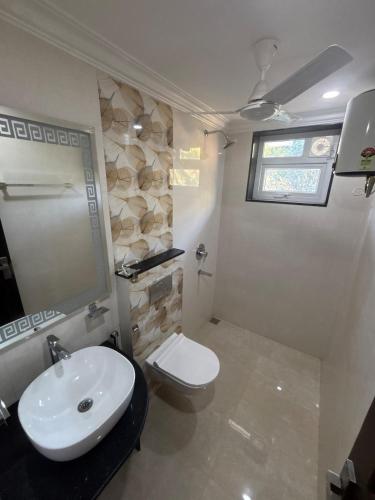 a bathroom with a white sink and a toilet at Monstera-Kudrat's Nilaya in Canacona