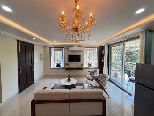 ein Wohnzimmer mit einer Couch und einem Kronleuchter in der Unterkunft Monstera-Kudrat's Nilaya in Canacona