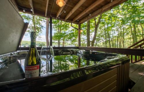 a bottle of wine and a glass in a tub at Lakefront Hot Tub Canoes Game Room Wood FP in Gouldsboro