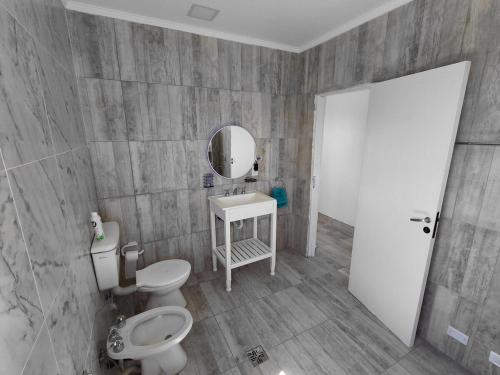 Un baño con inodoro, lavabo y espejo. en Libertad, Paz, Armonia, en Camet Norte