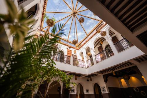 a building with a glass ceiling and a palm tree at Riad La Porte Rouge By La Siredrah in Marrakesh