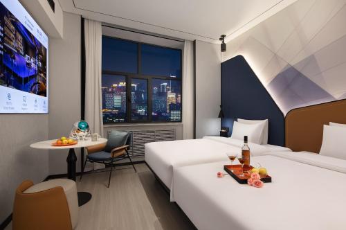 ein Hotelzimmer mit zwei Betten und einem Tisch in der Unterkunft Huanzhi Hotel Hulunbuir Hailar Railway Station Branch in Hulunber