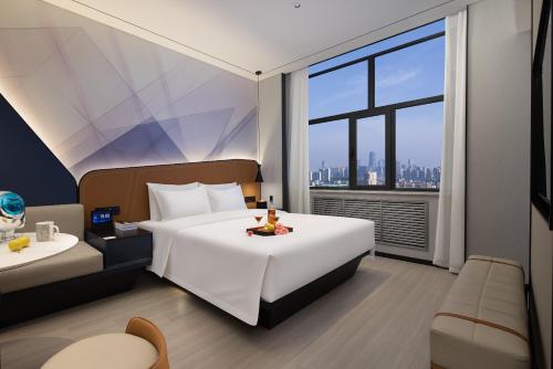 ein Hotelzimmer mit einem großen Bett und einem Fenster in der Unterkunft Huanzhi Hotel Hulunbuir Hailar Railway Station Branch in Hulunber