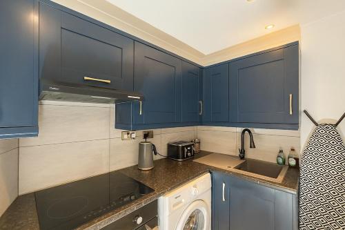 een keuken met blauwe kasten en een wastafel bij Modern Tiny Home - Ideal for Work Stays & Parking in Pocklington