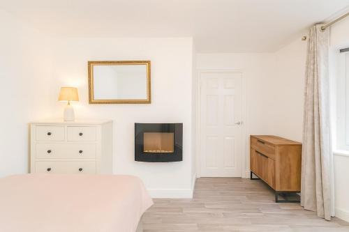 een witte slaapkamer met een bed en een open haard bij Modern Tiny Home - Ideal for Work Stays & Parking in Pocklington