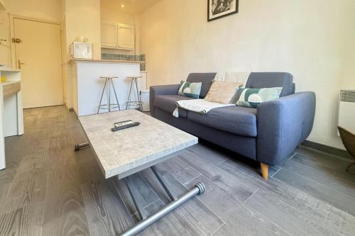 1-bedroom appartement in the center of Cannes في كان: غرفة معيشة مع أريكة زرقاء وطاولة قهوة