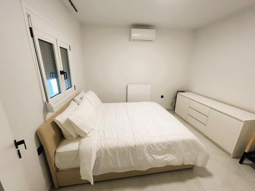 a white bedroom with a bed and a window at Ghini Venes 3 in Tríkala