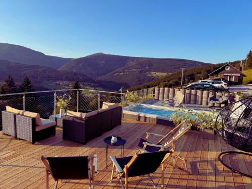a deck with chairs and a swimming pool with mountains at Bílá Labuť Pec in Pec pod Sněžkou