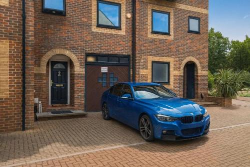 a blue car parked in front of a brick building at Iron House - Sleeps 11 - For Contractors & Families - Free Parking - Near Excel , Canary Wharf, O2, City AirPort & GreenWich in London