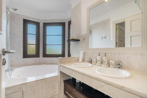 een badkamer met 2 wastafels, een bad en een spiegel bij Gadea Vistas in Caserío Capnegret