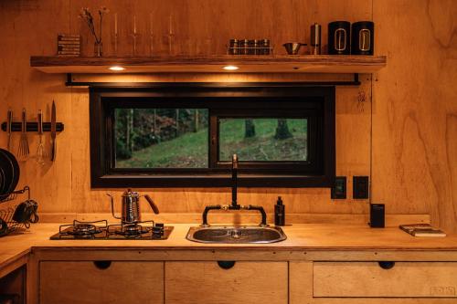 eine Küche mit einer Spüle, einem Herd und einem Fenster in der Unterkunft Cabana Fora in São Francisco de Paula